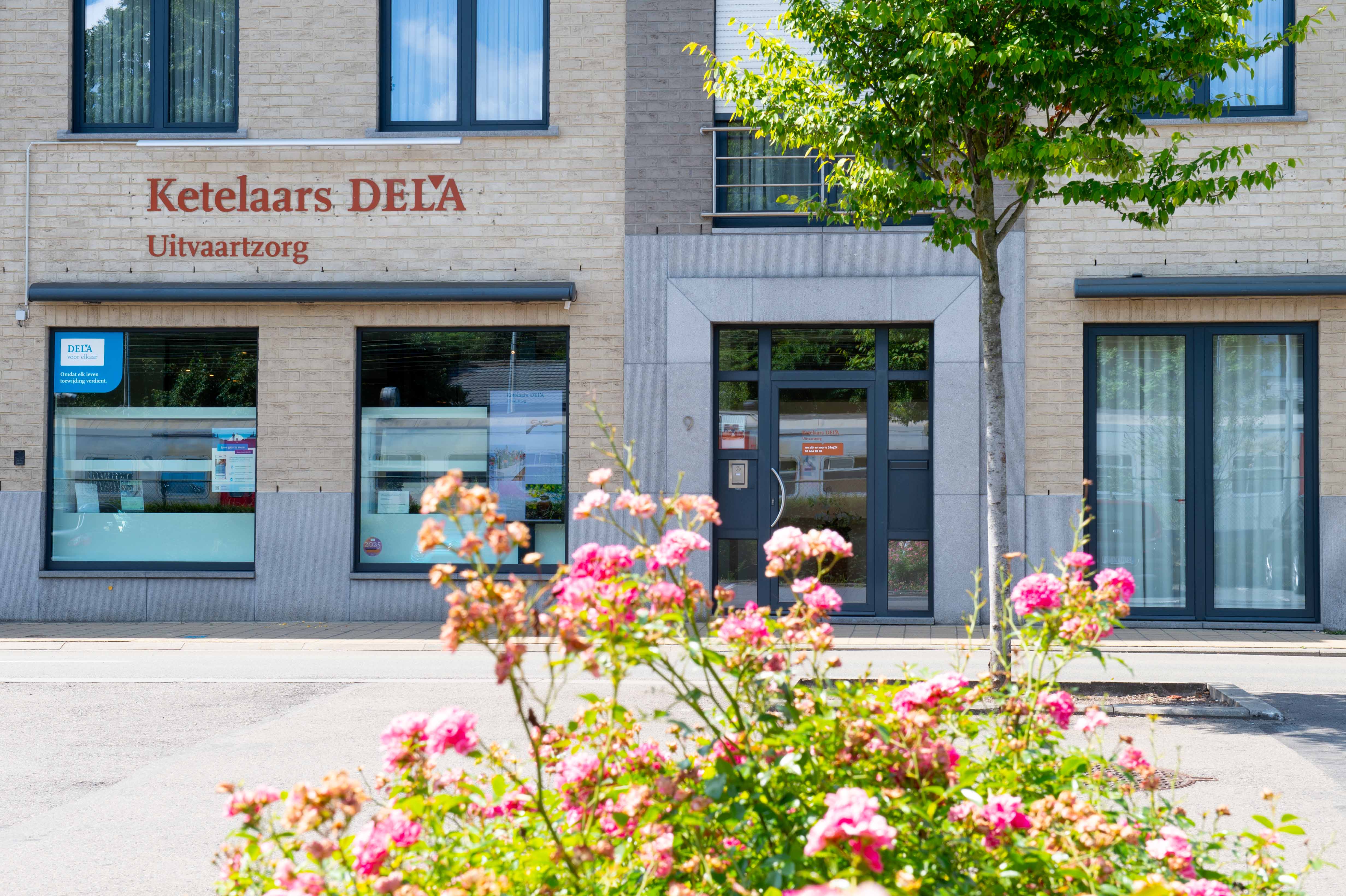 Contactinformatie van Ketelaars DELA Uitvaartzorg zichtbaar op het raam van het uitvaartcentrum in Kapellen.